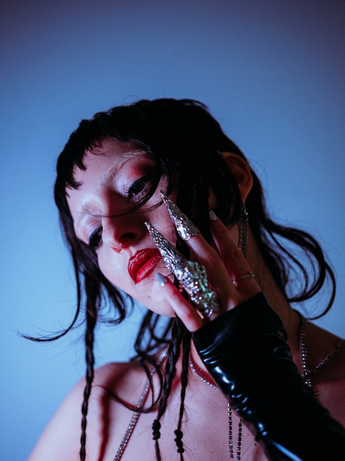 Lindred portrait with silver claw rings and red lips in blue light