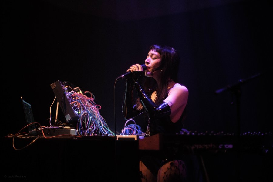 Lindred performing live on stage with modular synth and microphone